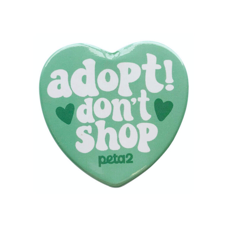 A teal heart-shaped enamel pin. It reads "Adopt! don't shop"